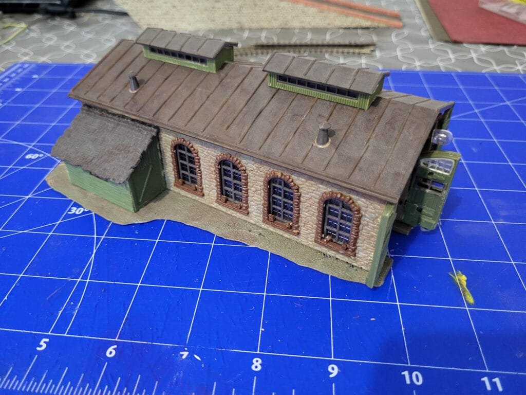 Miniature bâtiment hangar à locomotive en briques sur tapis découpe bleu