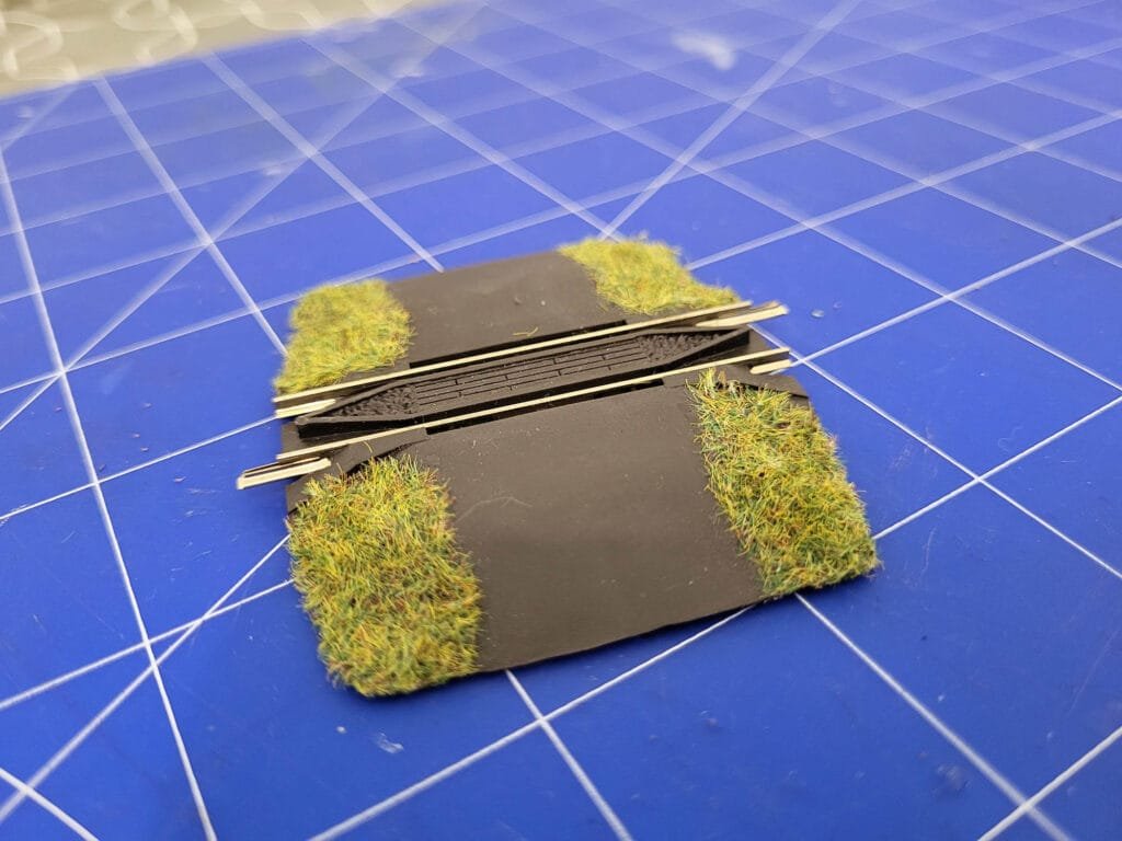 Passage à niveau non gardé avec herbe verte et débris