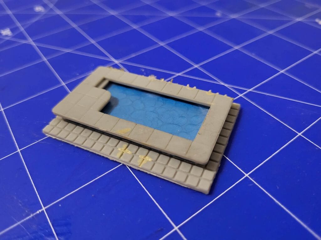 Piscine beige sur carrelage posée sur un tapis de découpe bleu