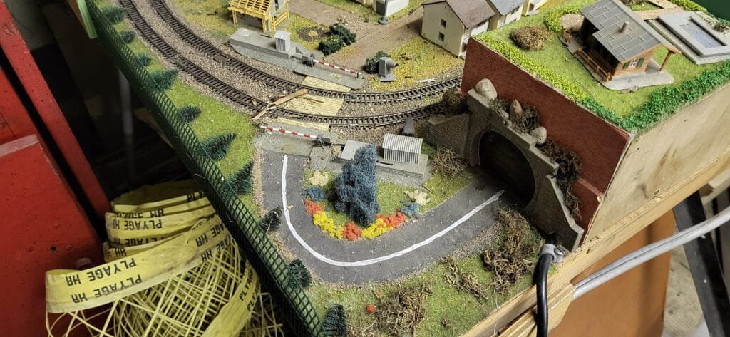 Maquette ferroviaire miniature avec trains, bâtiments, entrée de tunel et végétation