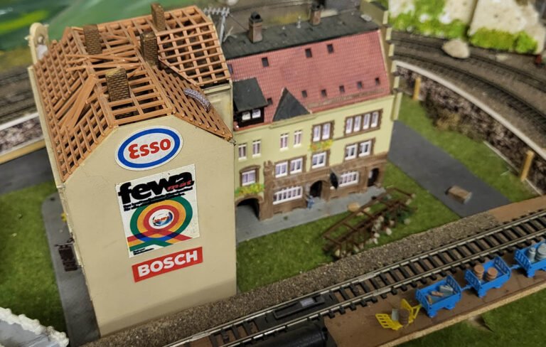 Maquette miniature gare avec panneaux Esso Fewa Bosch et voie ferroviaire