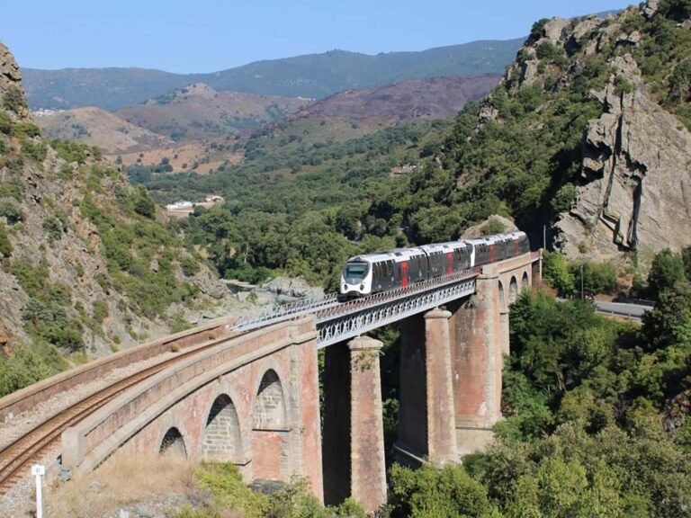 Train moderne traversant viaduc historique en montagne