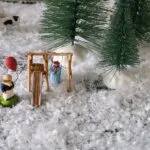 Figurines miniatures jouant dans la neige sous sapin