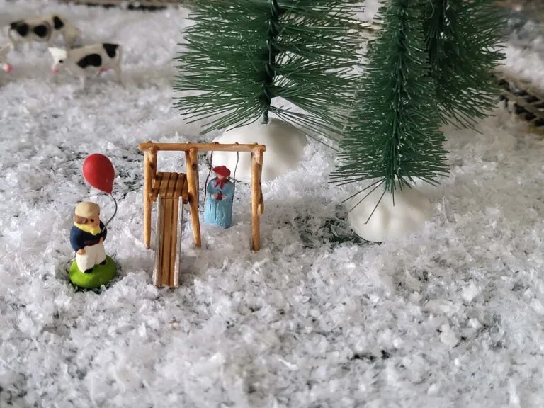 Figurines miniatures jouant dans la neige sous sapin