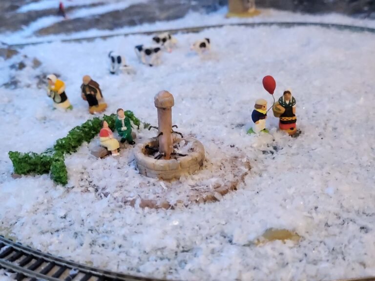Scène miniature hivernale avec figurines personnages et fontaine