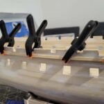Maquette de bateau en bois avec serre-joints noirs et orange maintenant assemblage bois menuiserie
